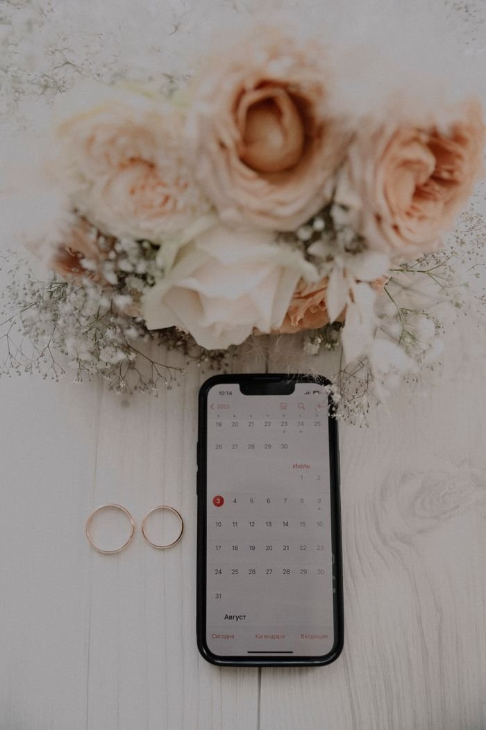 Wedding planning essentials with flowers, rings, and a digital calendar on display.